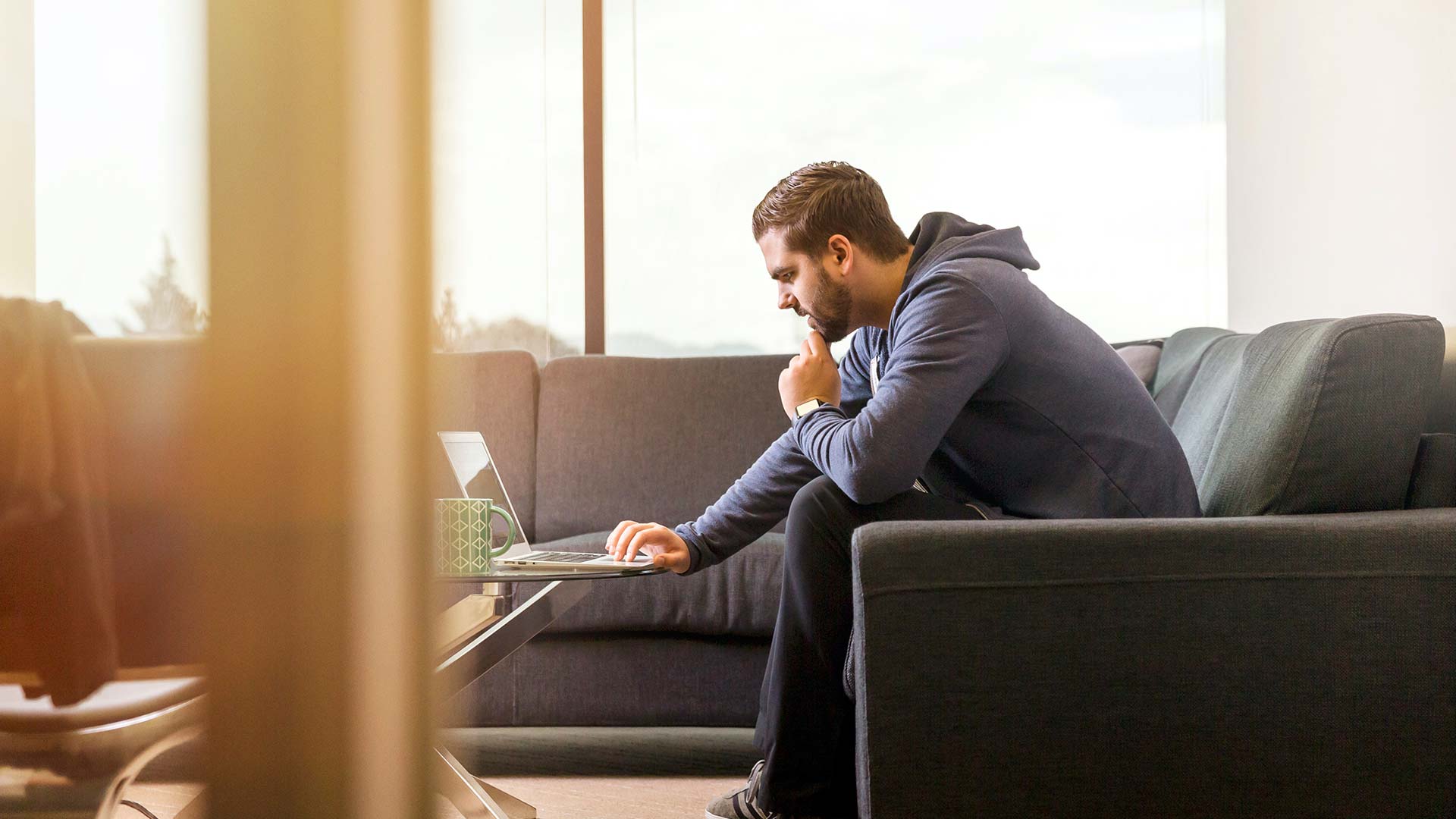 Asesoría y gestoría para emprendedores. Chico joven sentado en un sofá mirando la pantalla de un ordenador.